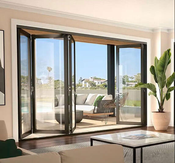 Open black framed bifold glass doors connecting a living room to an outdoor patio with lounge seating.